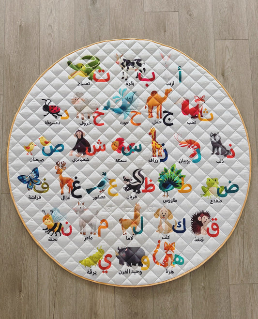 Round quilt with colorful animal illustrations and Arabic text on a wooden floor.