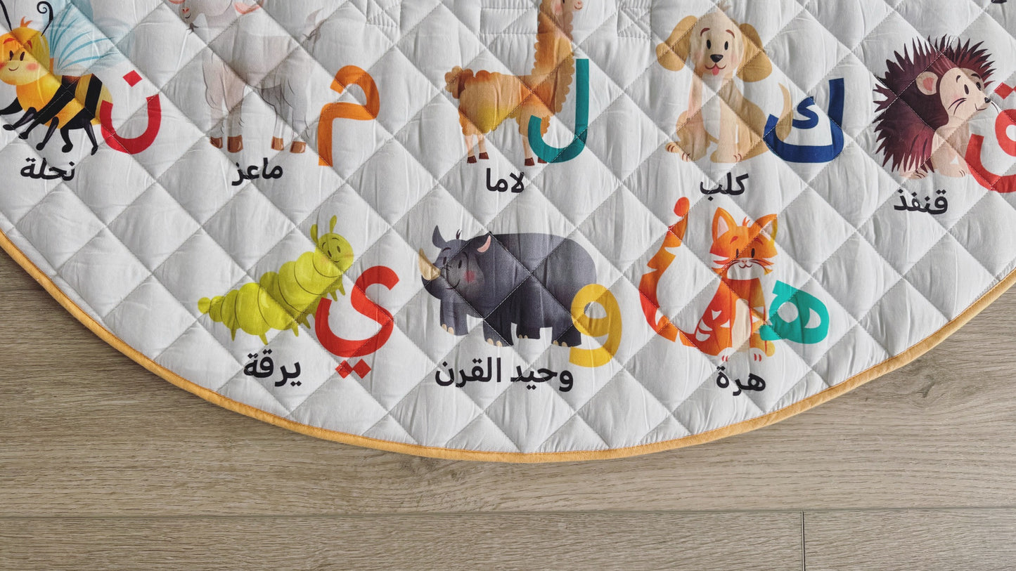 Children's educational rug with animal illustrations and Arabic text on a wooden floor.