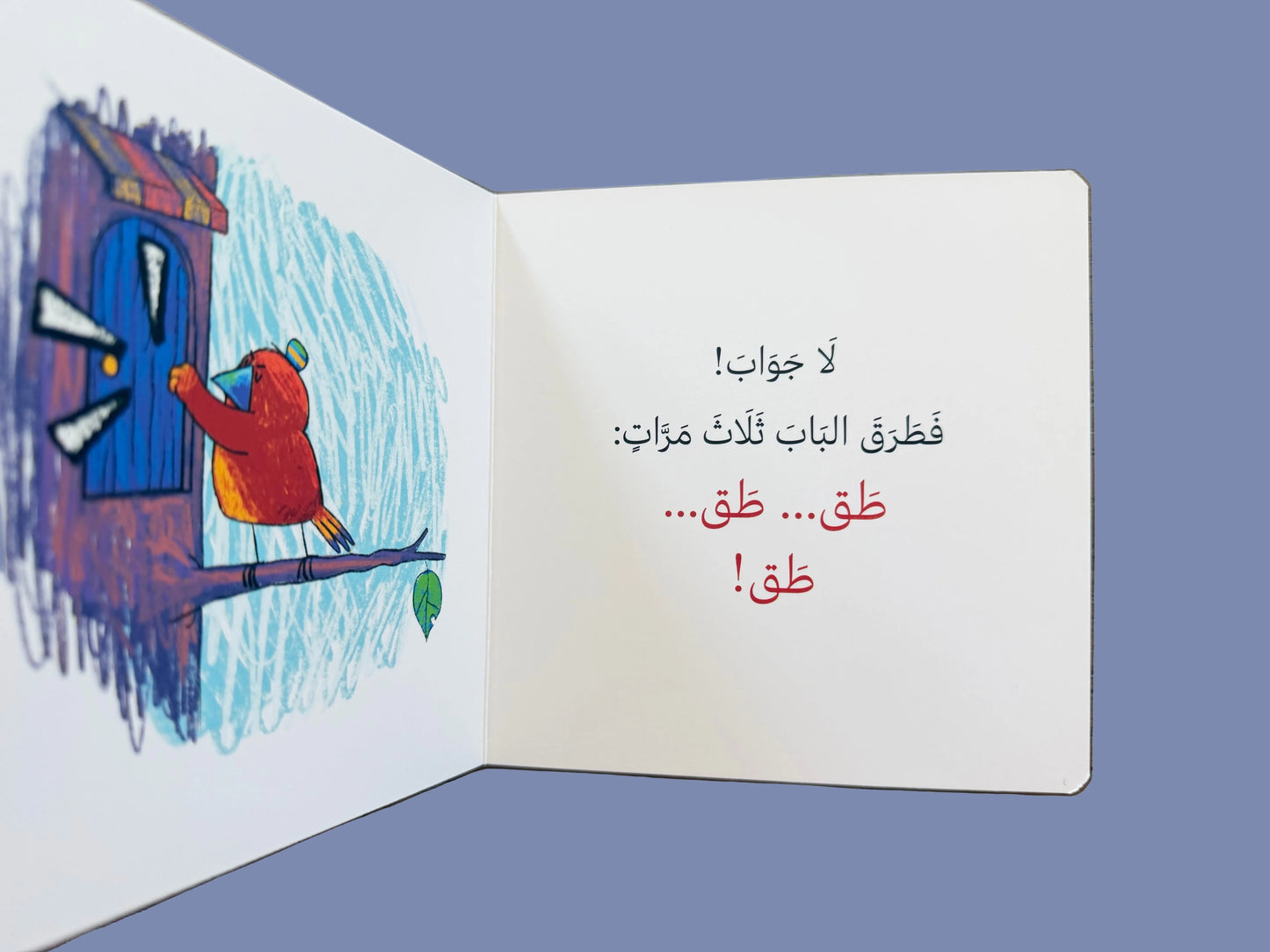 Open book with a colorful illustration of a child knocking on a door and Arabic text on a wooden surface.